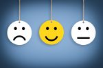 Frowning, smiling, and neutral emoji faces hanging from strings