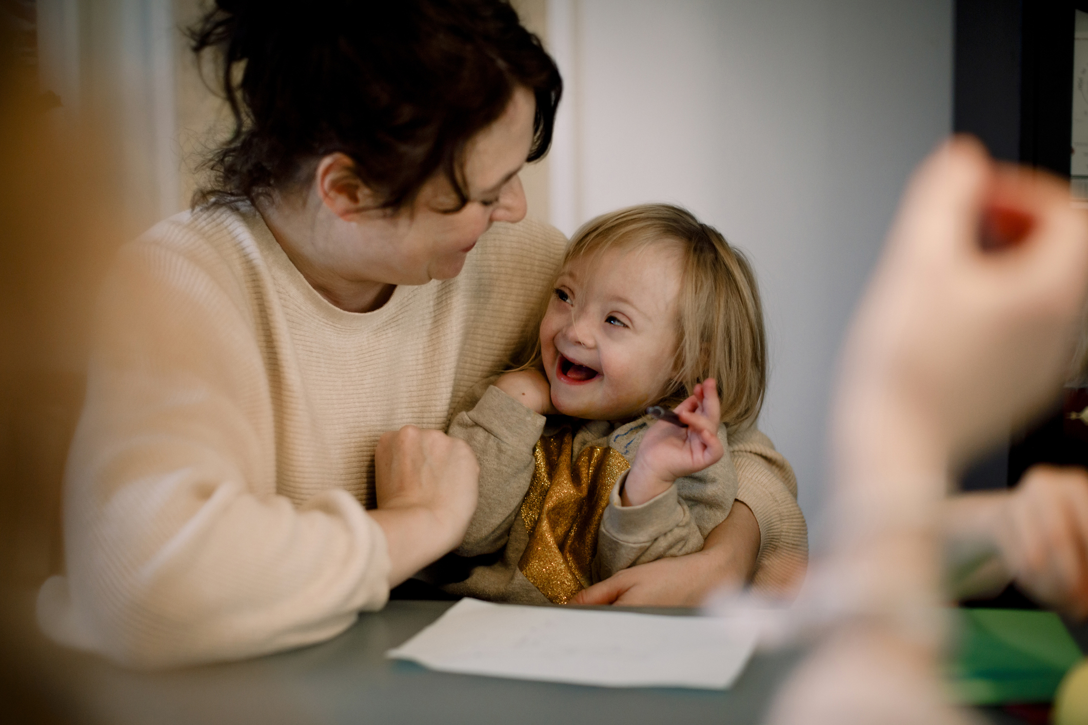 Smiling mother playing with disabled daughter while sitting by table at home